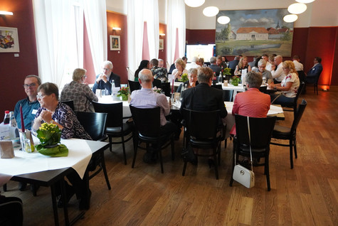 Blick in den Saal, wo die Gäste verteilt an mehreren Tischen sitzen - Klick öffnet Bildbetrachter