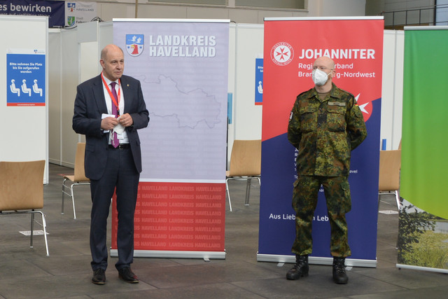 Zwei Männer stehen nebeneinander vor einem Aufsteller mit der Aufschrift "Landkreis Havelland".