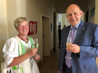 Eine Frau und ein Mann stehen mit einem Getränk in der Hand nebeneinander und schauen in die Kamera.