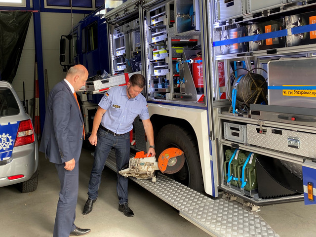 Landrat Lewandowski und Sebastian Lodwig vom THW stehen vor einem Gerätefahrzeug.