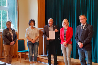 Fünf Personen stehen nebeneinander und schauen in die Kamera.