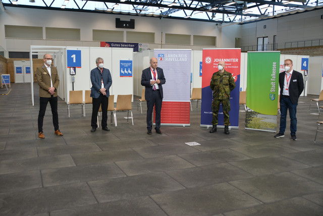Fünf Personen stehen mit Abstand nebeneinander im Impfzentrum. Der Landrat steht in der Mitte und spricht.