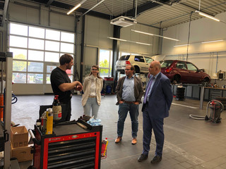 Klick öffnet Artikel, vier Personen in einer Autowerkstatt