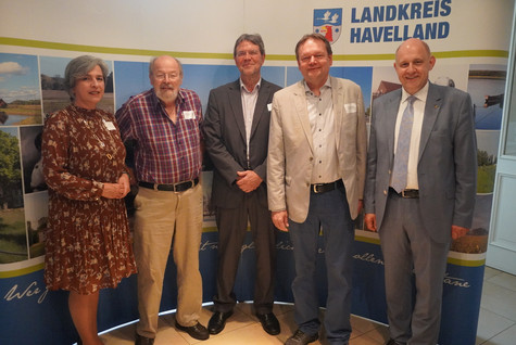 Der Landrat und die Kreistagsvorsitzende begrüßen die Gäste des Sommerempfangs vor einer Werbewand zum Landkreis Havelland - Klick öffnet Bildbetrachter