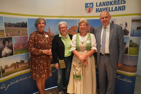 Der Landrat und die Kreistagsvorsitzende begrüßen die Gäste des Sommerempfangs vor einer Werbewand zum Landkreis Havelland - Klick öffnet Bildbetrachter