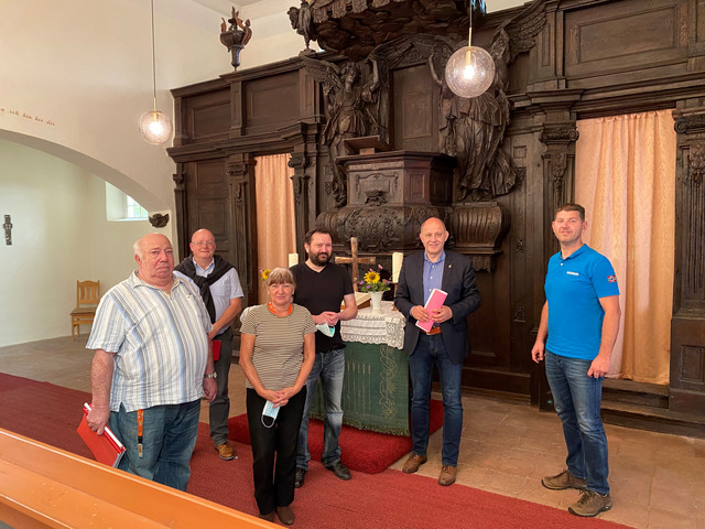 Sechs Personen stehen in der Kirche und schauen in die Kamera.