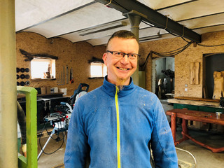 Holzbildhauer Jörg Richter steht in seiner Werkstatt - Klick öffnet Bildbetrachter