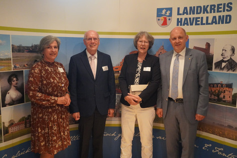 Der Landrat und die Kreistagsvorsitzende begrüßen die Gäste des Sommerempfangs vor einer Werbewand zum Landkreis Havelland - Klick öffnet Bildbetrachter