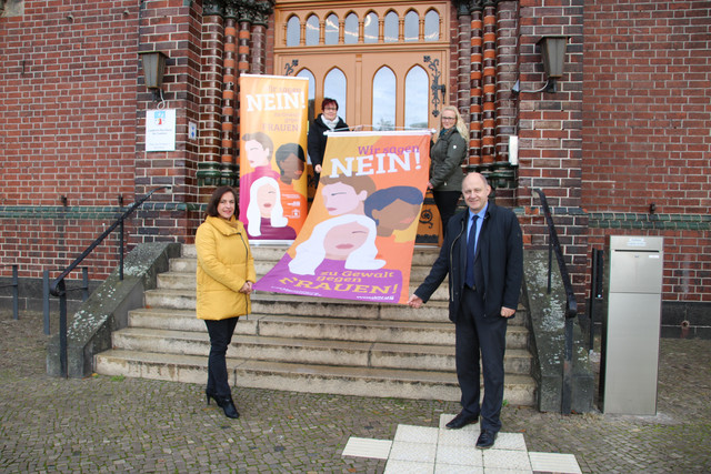 Vier Personen stehen verteilt auf einer Treppe und halten die Fahne zum Aktionstag.