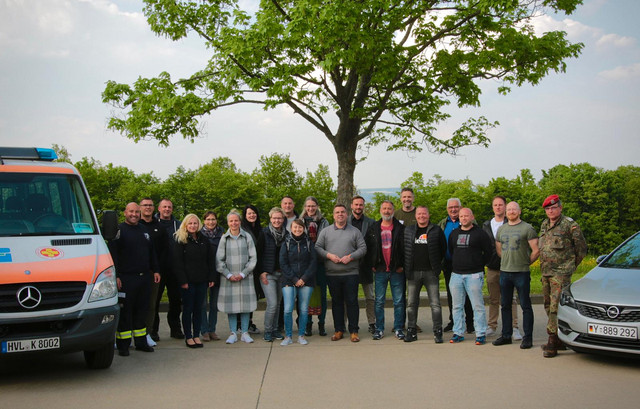 Eine Gruppe von Menschen steht zwischen zwei Autos.