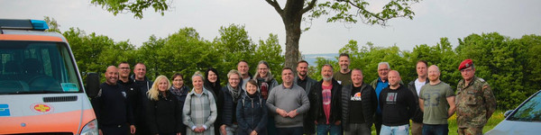 Eine Gruppe von Menschen steht zwischen zwei Autos.