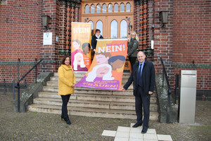 Vier Personen stehen verteilt auf einer Treppe und halten die Fahne zum Aktionstag.