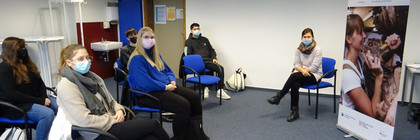 Eine Gruppe von Schülern sintzt mit der Referentin in einem Klassenraum.