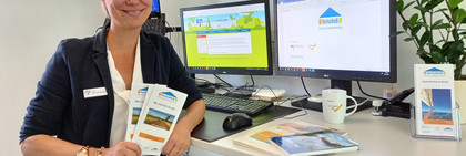 Eine Frau steht am Schreibtisch und hält Flyer in den Händen.