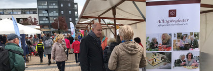 Klick öffnet Bildbetrachter, Mehrere Personen auf einem Platz an Ständen