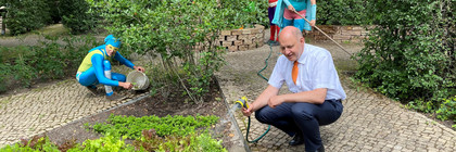 Landrat Roger Lewandowski gießt Blumen im Stinknormalen Stadtgarten von Rathenow.