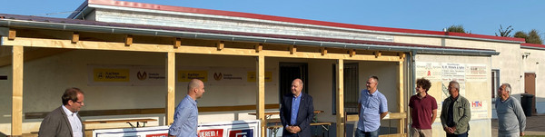 Sieben Männer stehen vor dem Vereinsgebäude.