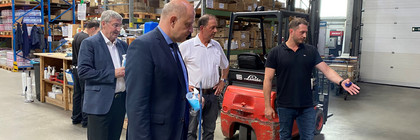 Vier Männer stehen in einer Lagerhalle, einer von ihnen zeigt auf etwas und redet.