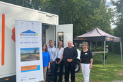 Fünf Personen stehen vor dem Beratungsmobil, im Hintergrund steht ein Pavillon mit Sitzmöglichkeiten - Klick öffnet Bildbetrachter
