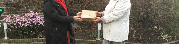 Zwie Frauen stehen im Garten, zwischen sich halten sie ein Päckchen.