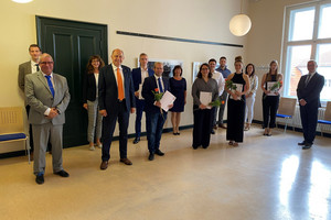 Die Absolventen sowie ihre Begleiter stehen mit Landrat Roger Lewandowski in einem Raum und schauen in die Kamera.