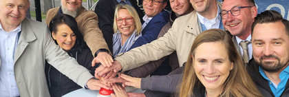 Der Landrat und Vertreter der havelländischen Kommunen stehen um einen Stehtisch und drücken den symbolischen Startbuzzer für die Landkreis-App - Klick öffnet Bildbetrachter