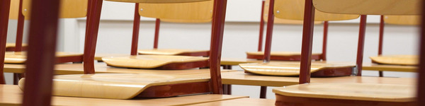 Blick in einen leeren Klassenraum: Die Stühle sind auf den Tischen abgestellt.