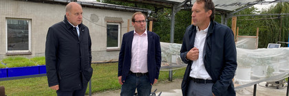 Drei Männer stehen im Halbkreis und unterhalten sich.