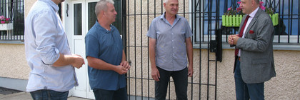 Landrat Lewandowski unterhält sich mit drei Mitgliedern des ESV Lok Elstal vor einem Vereinsgebäude.