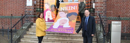 Vier Personen stehen verteilt auf einer Treppe und halten die Fahne zum Aktionstag.