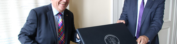 Kalligraph Bernd Thiel und Landrat Roger Lewandowski halten das neue Ehrenamtsbuch in die Kamera.