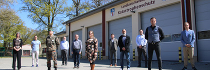 Die Mitglieder des havelländischen Corona-Krisenstabes stehen vor einer Fahrzeughalle.