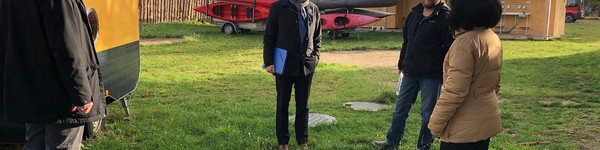 Vier Personen stehen in einigem Abstand auf einem Hof und unterhalten sich.