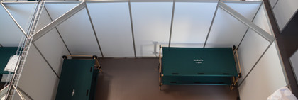 Blick von oben in eine Kabine des Willkommenszentrums: Zu sehen sind zwei Doppelstockbetten, ein Tisch und vier Stühle.