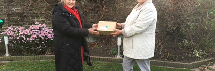 Zwie Frauen stehen im Garten, zwischen sich halten sie ein Päckchen.