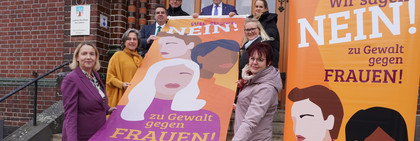 Klick öffnet Text; eine Gruppe von Menschen halten eine Fahne