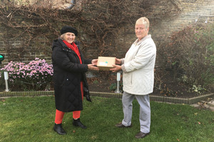 Zwie Frauen stehen im Garten, zwischen sich halten sie ein Päckchen.