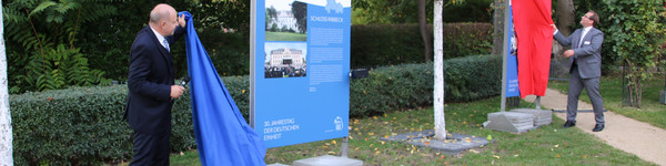 Landrat Roger Lewandowski und Nauens Bürgermeister Manuel Meger enthüllen zwei der Stelen, die mit einem Tuch verhüllt waren.