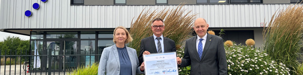 Drei Personen stehen vor dem Havelbus-Betriebshof und halten einen symbolischen Antrag in die Kamera - Klick öffnet Bildbetrachter.