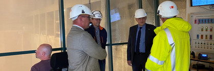 Vier Männer stehen im Kreis, im Hintergrund ist die Müllverbrennungsanlage zu sehen.