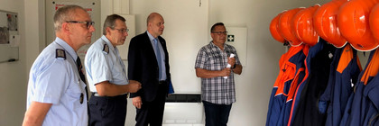 Vier Männer stehen in einem Umkleideraum der Feuerwehr.