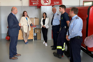 Der Landrat und einige andere Personen stehen im Feuerwehrgerätehaus und unterhalten sich.