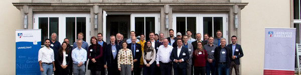 Klick öffnet Text, eine Gruppe von mehr als 30 Menschen vor einem Gebäude