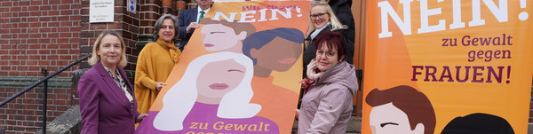 Klick öffnet Text; eine Gruppe von Menschen halten eine Fahne