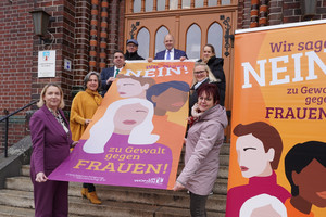 Klick öffnet Text; eine Gruppe von Menschen halten eine Fahne