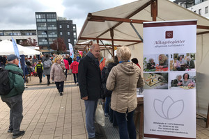 Klick öffnet Bildbetrachter, Mehrere Personen auf einem Platz an Ständen