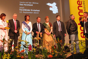 Kurz vor der Übergabe der Erntekrone auf der Antenne Brandenburg-Bühne v.l.: Moderatorin Marina Ringel, Landrat Dr. Burkhard Schröder, Ketziner Fischerkönigin Jennifer Kiesewalter, Ketziner Bürgermeister Bernd Lück, 2. Havelländer Erntekönigen Mandy Hinze, Friesacks Amtsdirektor Christian Pust, Geschäftsführer des MAFZ-Erlebnispark-Paaren, Gerhard Weiß, und Moderator Carsten Gohlke.