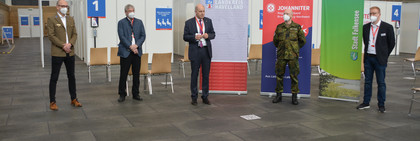 Fünf Personen stehen mit Abstand nebeneinander im Impfzentrum. Der Landrat steht in der Mitte und spricht.