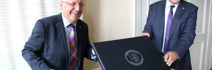 Kalligraph Bernd Thiel und Landrat Roger Lewandowski halten das neue Ehrenamtsbuch in die Kamera.