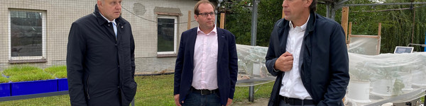 Drei Männer stehen im Halbkreis und unterhalten sich.